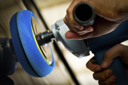 Man using a power polisher on a car