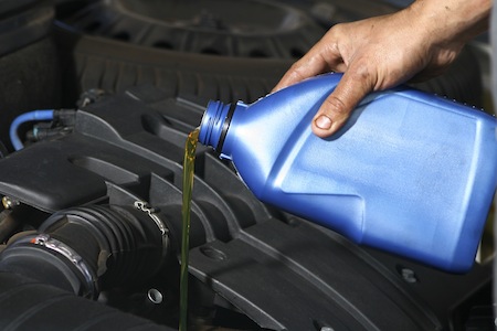 Man pouring oil into a car